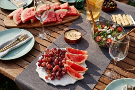 Photo for Close up of fresh fruits and berries assortment on picnic table set for dinner party outdoors, copy space - Royalty Free Image