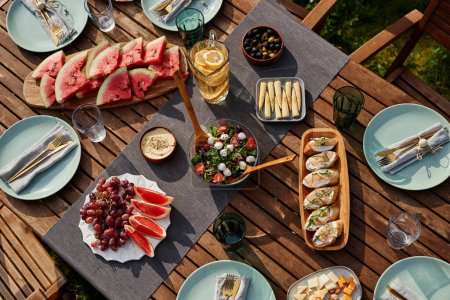 Photo for Top view image of wooden dinner table set for Summer party outdoors with fresh fruits and berries - Royalty Free Image