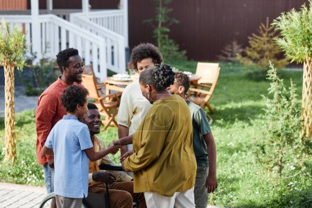 Téléchargez les photos : Portrait de grande famille afro-américaine avec personne en fauteuil roulant bavardant à l'extérieur pendant la fête d'été - en image libre de droit