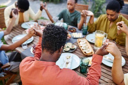 Foto de Vista de alto ángulo en la familia afroamericana diciendo gracia en la mesa al aire libre y tomados de la mano durante la reunión - Imagen libre de derechos