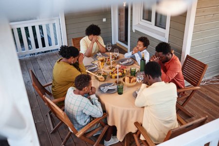 Foto de Vista de ángulo alto en la familia afroamericana diciendo gracia en la mesa de la cena con los ojos cerrados - Imagen libre de derechos