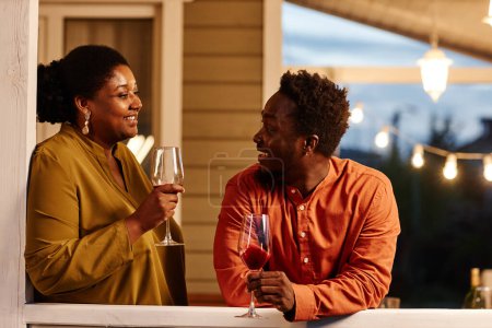 Photo for Portrait of young African American couple enjoying wine at house terrace in evening - Royalty Free Image