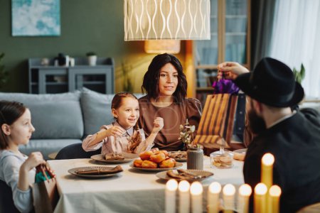 Foto de Retrato de la familia judía moderna disfrutando de la cena juntos en casa y jugando dreidel, espacio de copia - Imagen libre de derechos