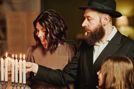 Foto de Retrato de vista lateral de la vela menorah de iluminación familiar judía ortodoxa durante la celebración de Hanukkah - Imagen libre de derechos