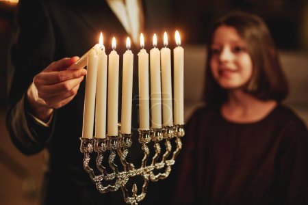 Foto de Primer plano del hombre judío encendiendo la vela de plata menorah durante la celebración de Hanukkah, espacio de copia - Imagen libre de derechos