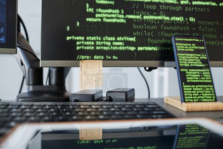 Foto de Primer plano del lugar de trabajo de los programadores con el teclado de ordenadores y líneas de código verde en la pantalla - Imagen libre de derechos