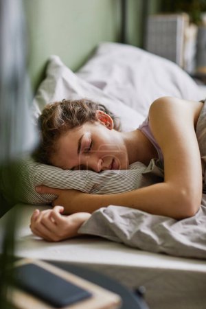 Foto de Mujer joven cansada durmiendo en su cómoda cama en el dormitorio - Imagen libre de derechos
