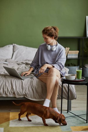 Foto de Chica sentada en la cama y el uso de la computadora portátil durante el desayuno por la mañana - Imagen libre de derechos