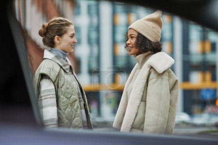 Photo for Two friends in warm clothing talking to each other while meeting in the city - Royalty Free Image