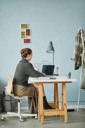 Téléchargez les photos : Vue arrière de la jeune femme d'affaires travaillant sur ordinateur portable à la table au bureau - en image libre de droit
