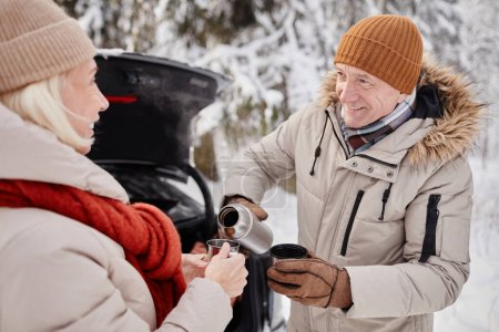 Téléchargez les photos : Portrait taille haute de couple mature heureux bénéficiant d'une tasse de coco chaud à l'extérieur en hiver - en image libre de droit