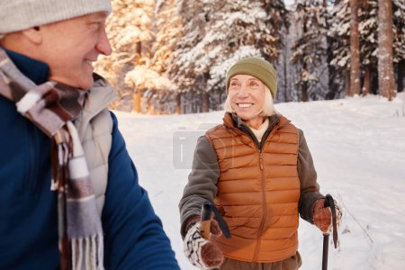 Téléchargez les photos : Portrait de femme âgée souriante marchant avec des bâtons dans la forêt d'hiver avec son mari - en image libre de droit