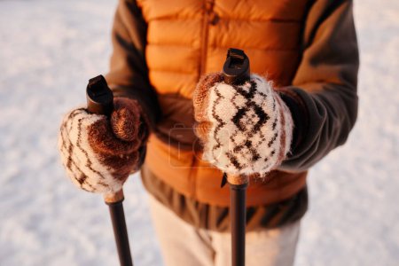 Téléchargez les photos : Gros plan de la femme tenant des bâtons nordiques en hiver avec un accent sur les mitaines de laine, espace de copie - en image libre de droit