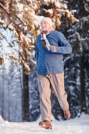 Téléchargez les photos : Portrait vertical complet d'un aîné sportif courant dans une forêt d'hiver - en image libre de droit