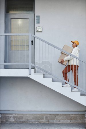 Foto de Gráfica mínima toma de repartidor subiendo escaleras a la puerta de la casa - Imagen libre de derechos