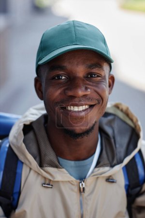 Foto de Retrato vertical del hombre afroamericano sonriente como trabajador de reparto de comida en la ciudad - Imagen libre de derechos