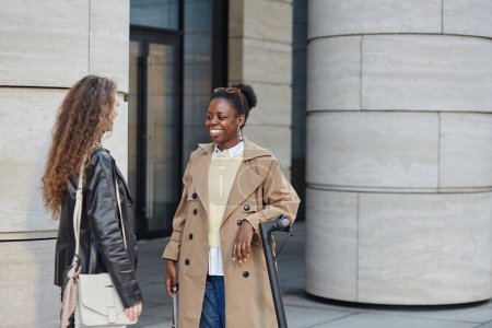 Foto de Retrato de una joven mujer negra hablando con un amigo en el entorno de la ciudad y usando abrigo, espacio para copiar - Imagen libre de derechos