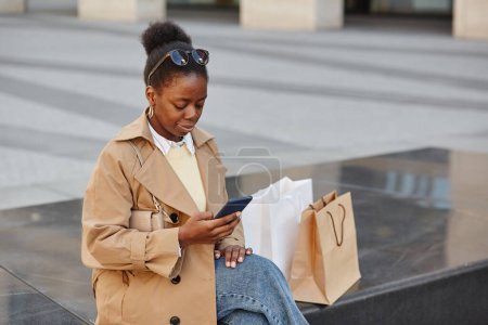 Foto de Retrato de ángulo alto de una joven negra usando un teléfono inteligente en el centro de la ciudad después del día de compras, espacio para copiar - Imagen libre de derechos