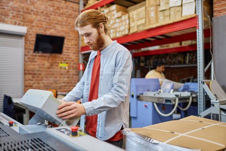 Photo for Waist up portrait of bearded young man setting up printing machine in workshop, copy space - Royalty Free Image