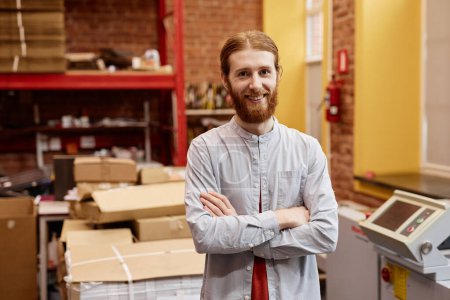 Photo for Waist up portrait of smiling young man working in industrial printing shop and standing with arms crossed, copy space - Royalty Free Image