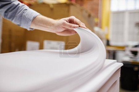 Téléchargez les photos : Gros plan de la personne vérifiant la qualité de la pile de papier dans l'imprimerie, espace de copie - en image libre de droit