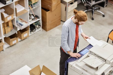 Foto de Vista superior en el hombre joven usando la máquina de copiar en la tienda industrial, espacio de copia - Imagen libre de derechos