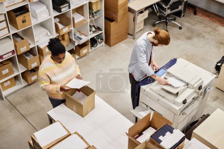 Photo for Top view of two workers using copying machine at printing factory, copy space - Royalty Free Image