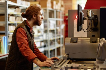 Foto de Retrato de vista lateral de trabajador masculino que opera la máquina de impresión en la fábrica de impresión - Imagen libre de derechos