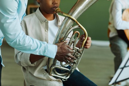 Photo for Close-up of hand of young African American music teacher helping pre-teen schoolboy with wind instrument during lesson - Royalty Free Image