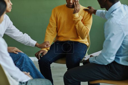 Photo for Cropped shot of upset multi-ethnic schoolboy and support group of African American male psychologist and classmates comforting him - Royalty Free Image