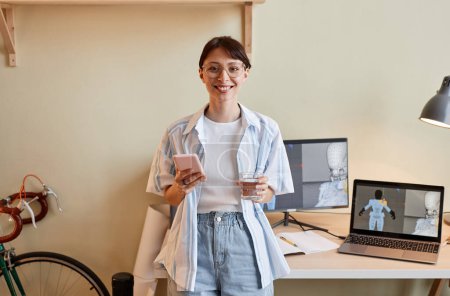 Téléchargez les photos : Portrait taille haute de jeune femme créative en tant que concepteur 3D numérique souriant à la caméra par lieu de travail, espace de copie - en image libre de droit