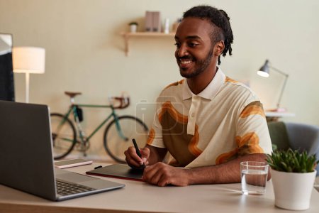 Téléchargez les photos : Portrait d'un homme noir souriant en tant qu'artiste numérique ou photographe utilisant une tablette de stylo sur le lieu de travail - en image libre de droit