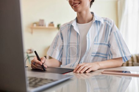 Téléchargez les photos : Gros plan de la jeune femme souriante utilisant une tablette de stylo pour la conception numérique au bureau à domicile, espace de copie - en image libre de droit