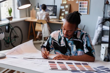 Téléchargez les photos : Portrait d'homme noir créatif travaillant sur des plans d'étage pour le projet de design d'intérieur, espace de copie - en image libre de droit