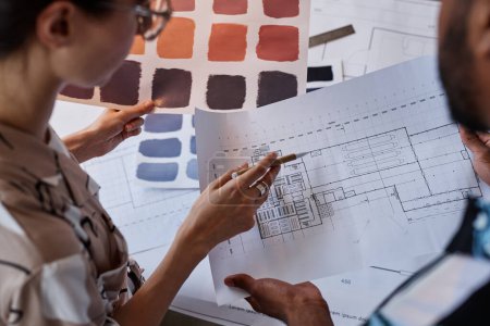 Photo for Close up of two architects discussing floor plans and color swatches for interior design project - Royalty Free Image
