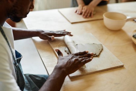 Foto de Primer plano de manos masculinas dando forma a la arcilla mientras disfruta de clase de arte en el estudio de cerámica, espacio de copia - Imagen libre de derechos