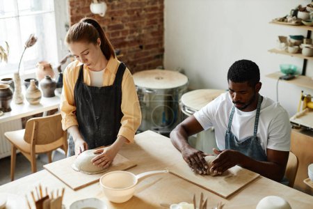 Téléchargez les photos : Portrait grand angle de deux personnes faisant de la céramique à la main dans un studio de poterie confortable, espace de copie - en image libre de droit