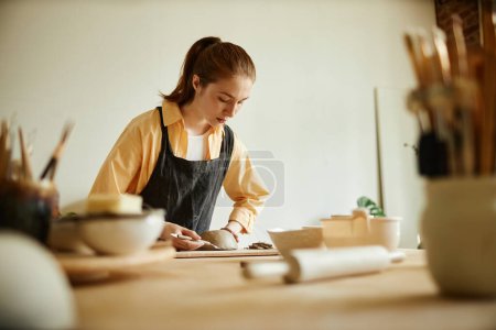 Photo for Warm toned portrait of young female artist creating handmade ceramic bowl in cozy pottery studio, copy space - Royalty Free Image