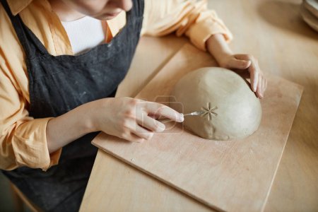 Foto de Primer plano de artista femenina decorando cuenco de cerámica hecho a mano en el estudio de cerámica, espacio de copia - Imagen libre de derechos