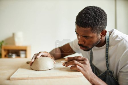 Téléchargez les photos : Portrait minimal d'un artiste masculin décorant un bol en céramique fait à la main dans un atelier de poterie, espace de copie - en image libre de droit