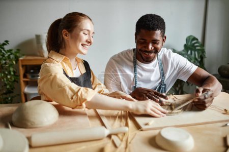 Foto de Retrato de pareja joven despreocupada disfrutando de taller de cerámica juntos y haciendo cerámica hecha a mano - Imagen libre de derechos