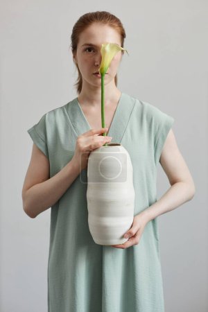 Photo for Fir young woman holding handmade ceramic vase with calla lily flower - Royalty Free Image