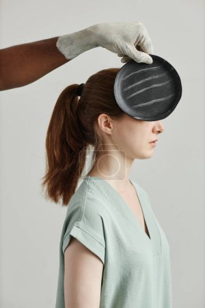 Foto de Concepto de fotografía de artista cubriendo el rostro de una joven con cerámica negra hecha a mano - Imagen libre de derechos