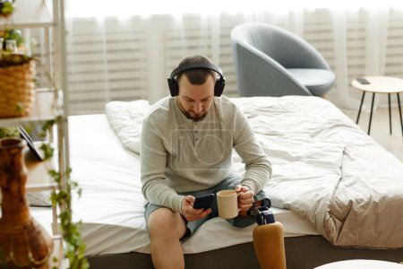 Téléchargez les photos : Portrait en grand angle d'un homme avec prothèse de jambe profitant du matin à la maison et écoutant de la musique avec écouteurs, espace de copie - en image libre de droit