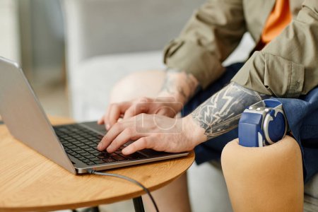 Photo for Closeup of man with prosthetic leg using laptop while working, copy space - Royalty Free Image