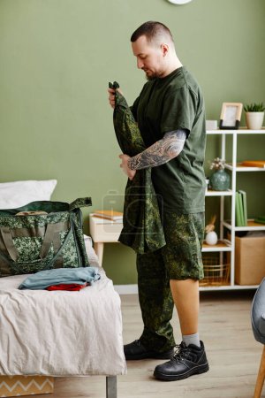 Téléchargez les photos : Vue de côté portrait d'un vétéran militaire avec prothèse jambe emballage uniforme de l'armée - en image libre de droit