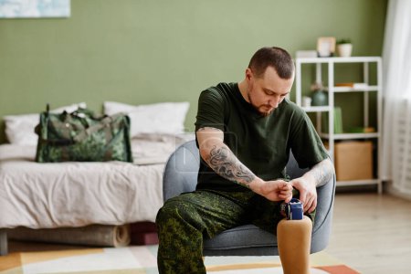 Photo for Portrait of military veteran fixing prosthetic leg and wearing army uniform, copy space - Royalty Free Image
