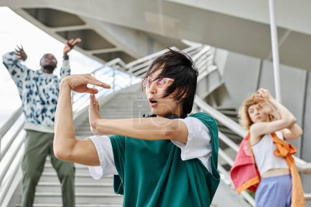 Foto de Diverso grupo de jóvenes bailando al aire libre y usando ropa de estilo callejero se centran en el hombre asiático en primer plano - Imagen libre de derechos