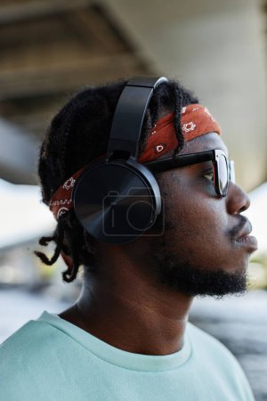 Foto de Vista del perfil de un joven negro con auriculares en un entorno urbano al aire libre - Imagen libre de derechos