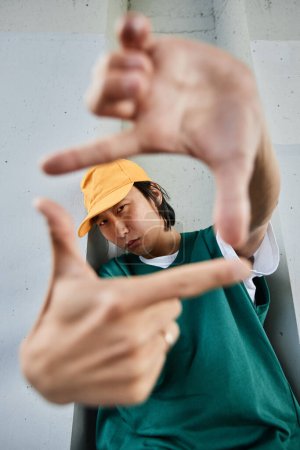 Téléchargez les photos : Portrait vertical de jeune homme asiatique portant des vêtements colorés de style de rue et caméra de cadrage - en image libre de droit